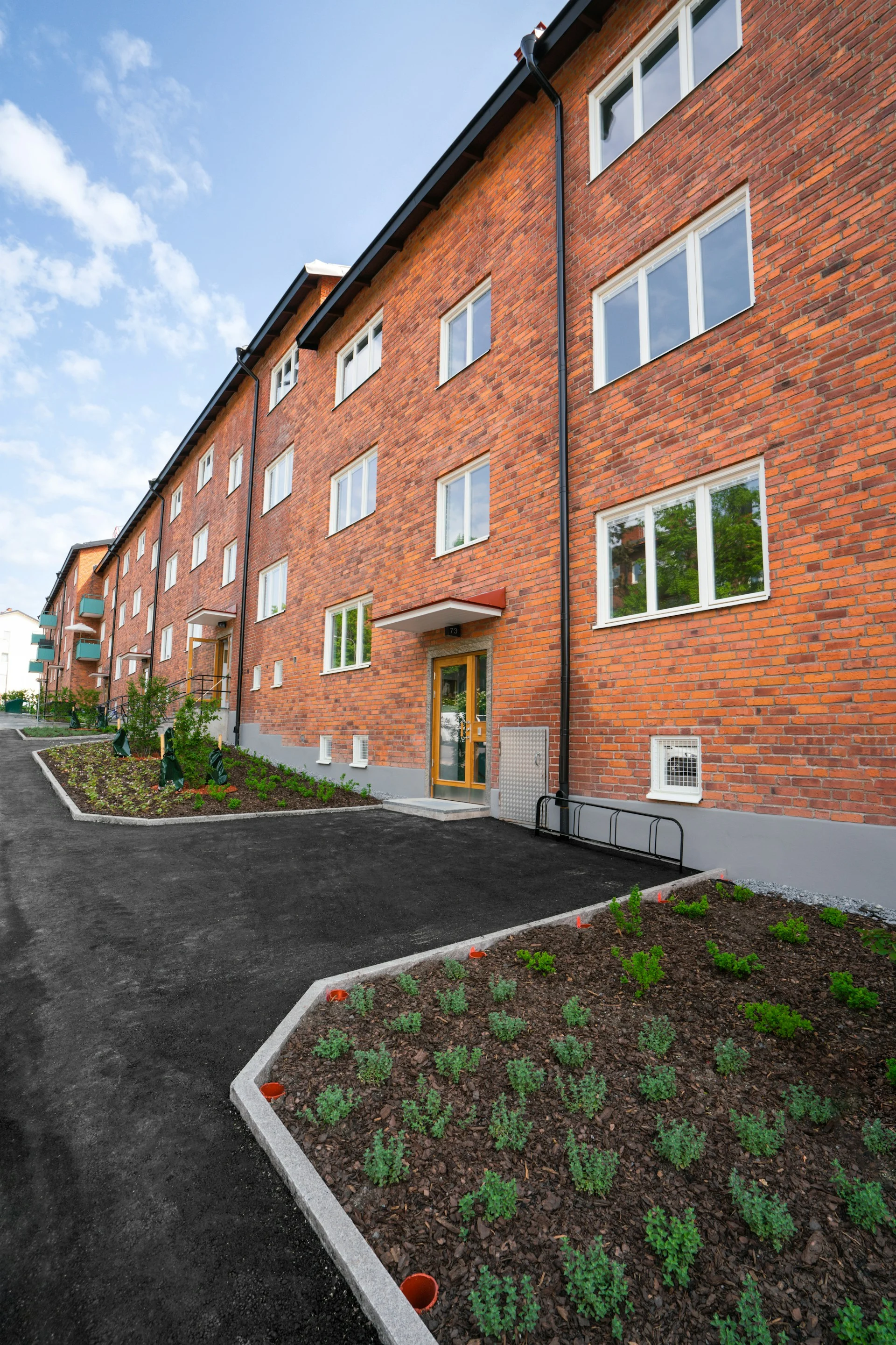 Brick apartment building with landscaped entrance.